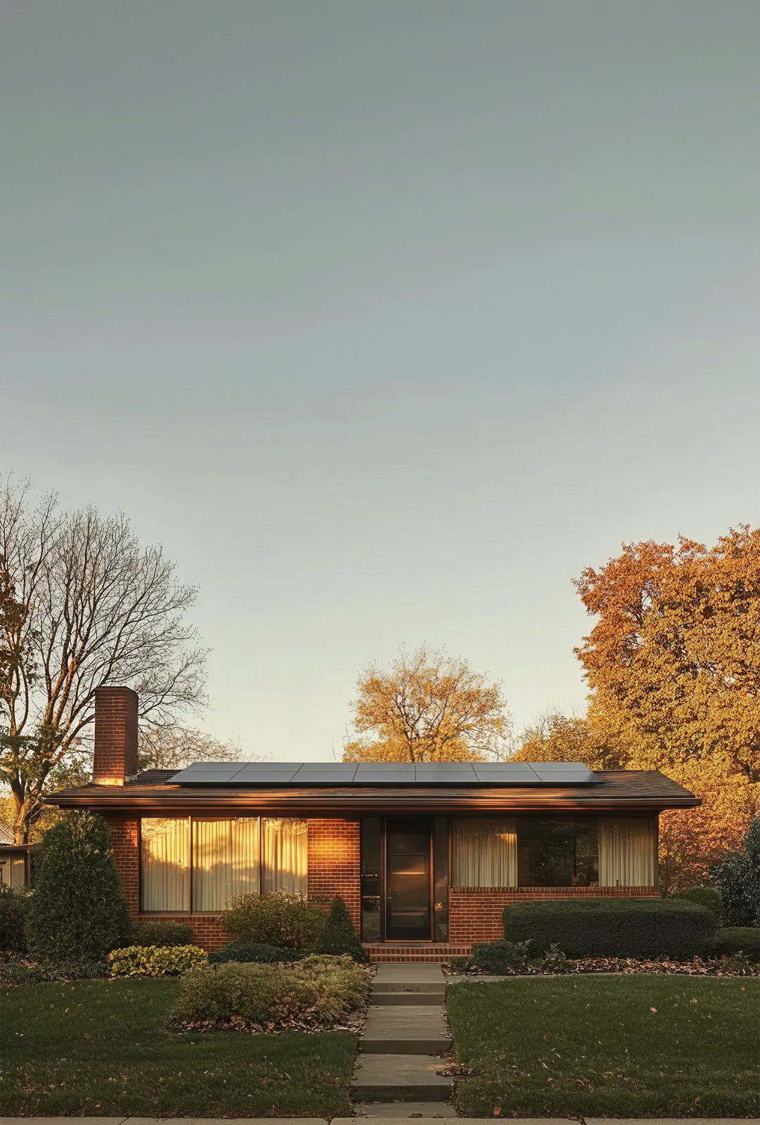 A home with solar panels at sunset, warm golden hour light on brick and autumn trees